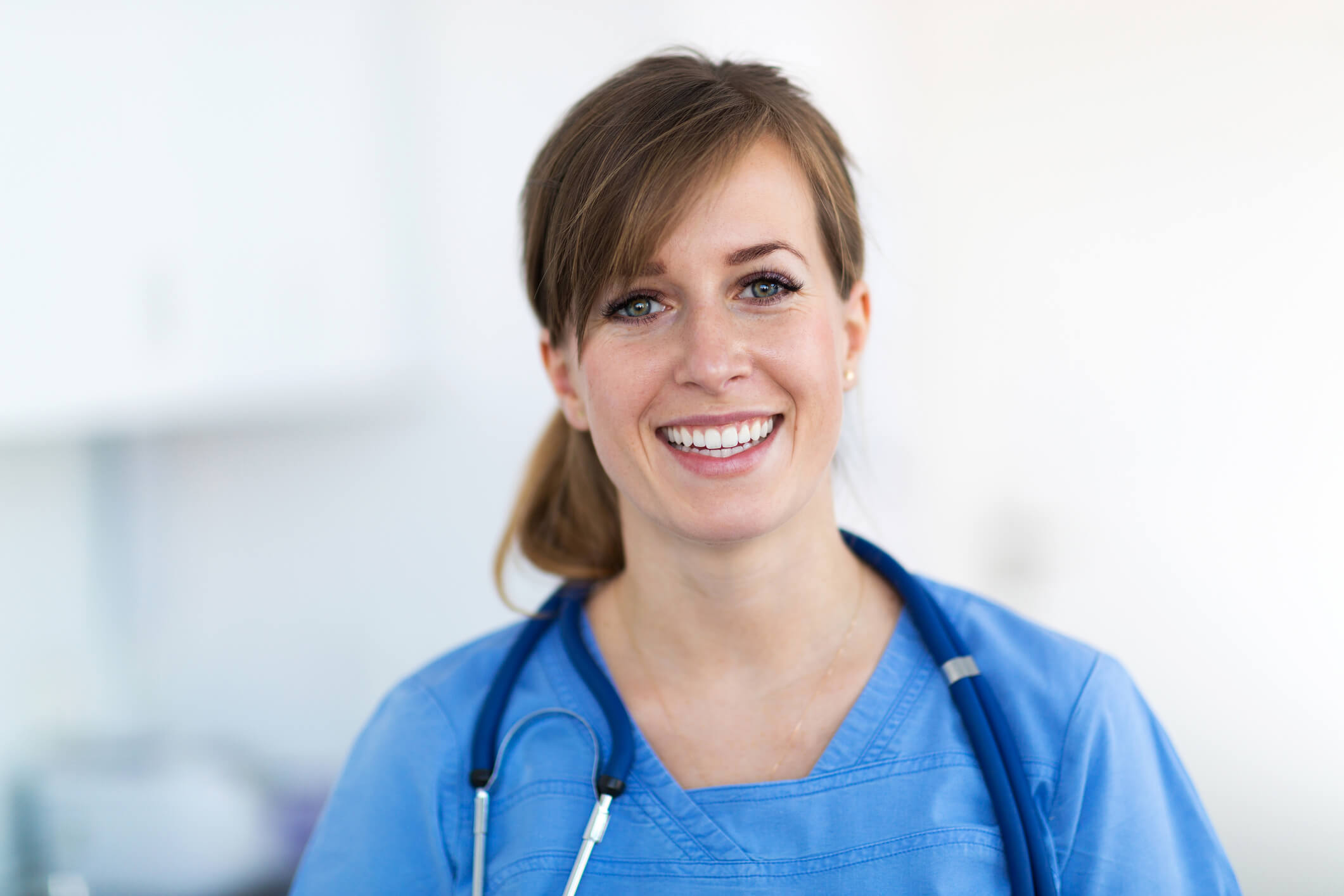 woman smiling in scrubs with a stethoscope around her neck